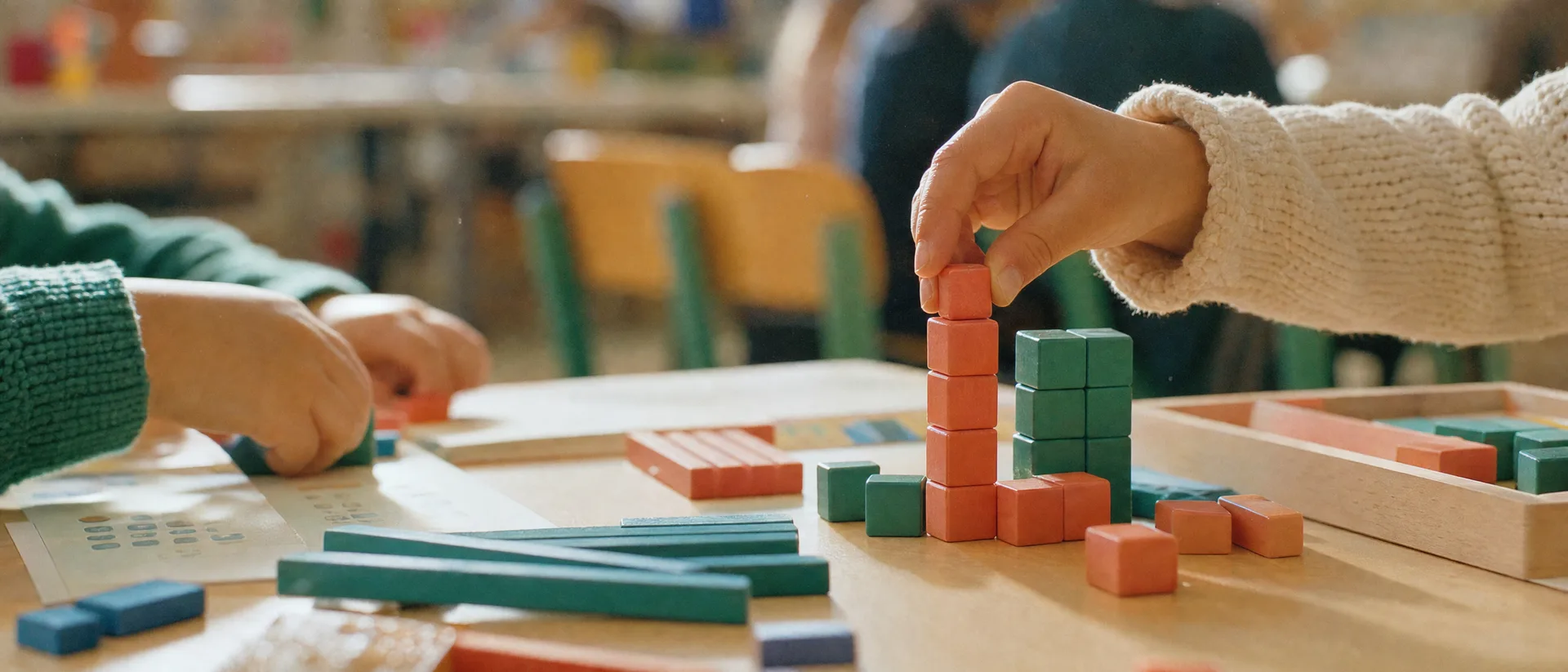 Des mains d'enfants manipulent du matériel de numération sur un bureau