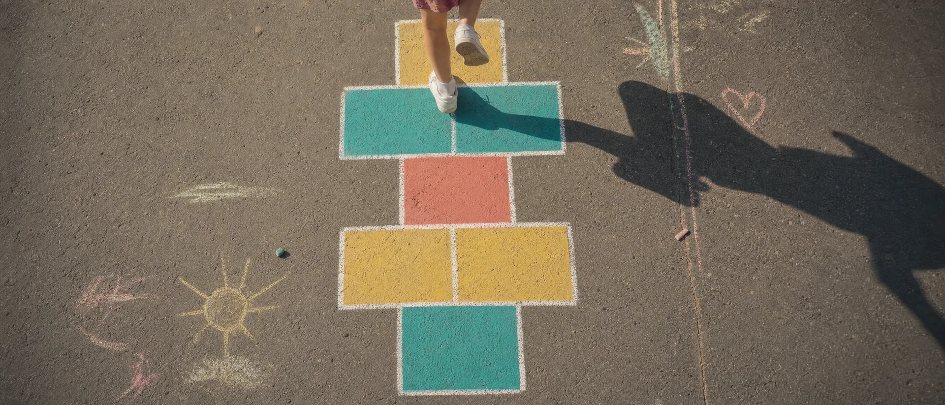 Une marelle peinte en couleurs vue du dessus, une enfant saute une case